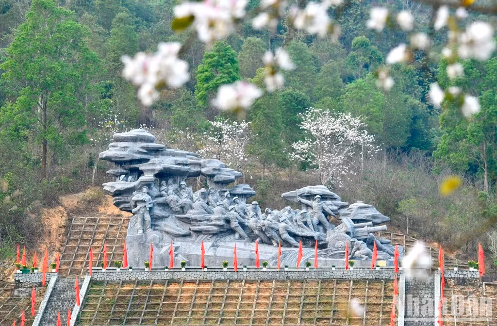 Les fleurs de bauhinie à côté du monument représentant des soldats tirant des pièces d’artillerie dans la commune de Nà Nhan, ville de Diên Biên Phu. Photo : nhandan.vn