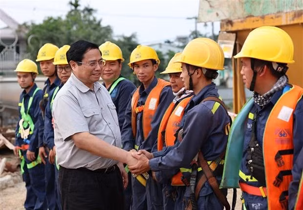Le Premier ministre Pham Minh Chinh et des ouvriers qui construisent le pont Nguyên Hoàng sur la rivière Huong. Photo : VNA.