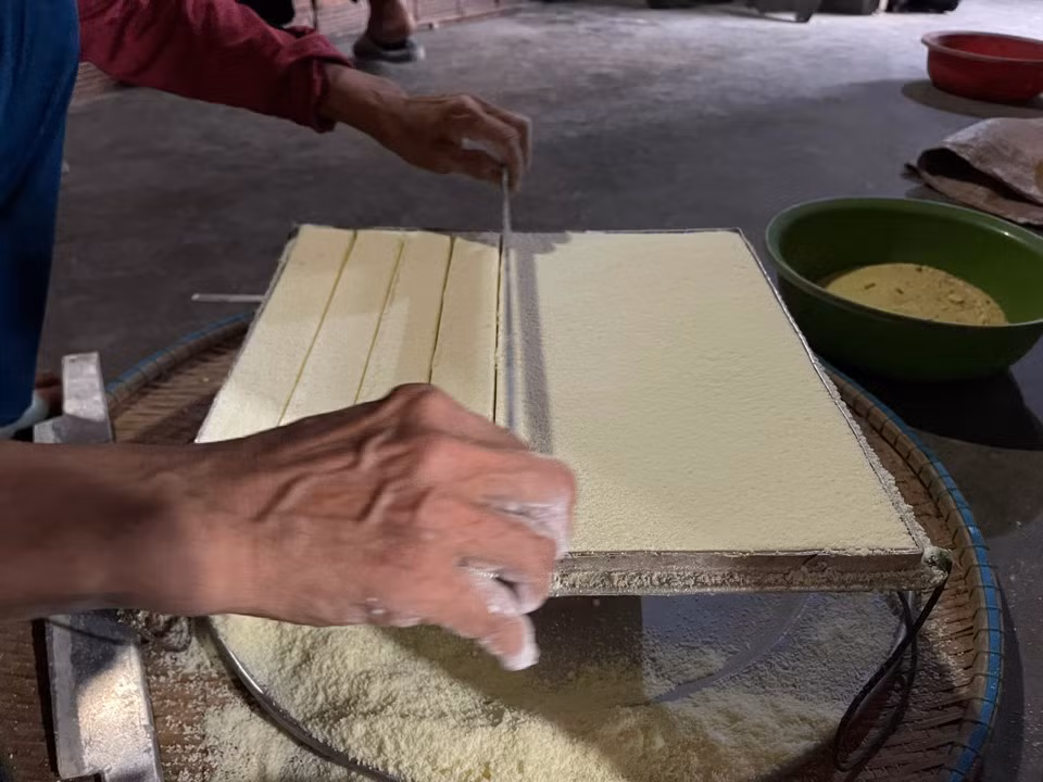 La farine de riz est ensuite pressée dans le moule pour former des petits biscuits de forme carrée.