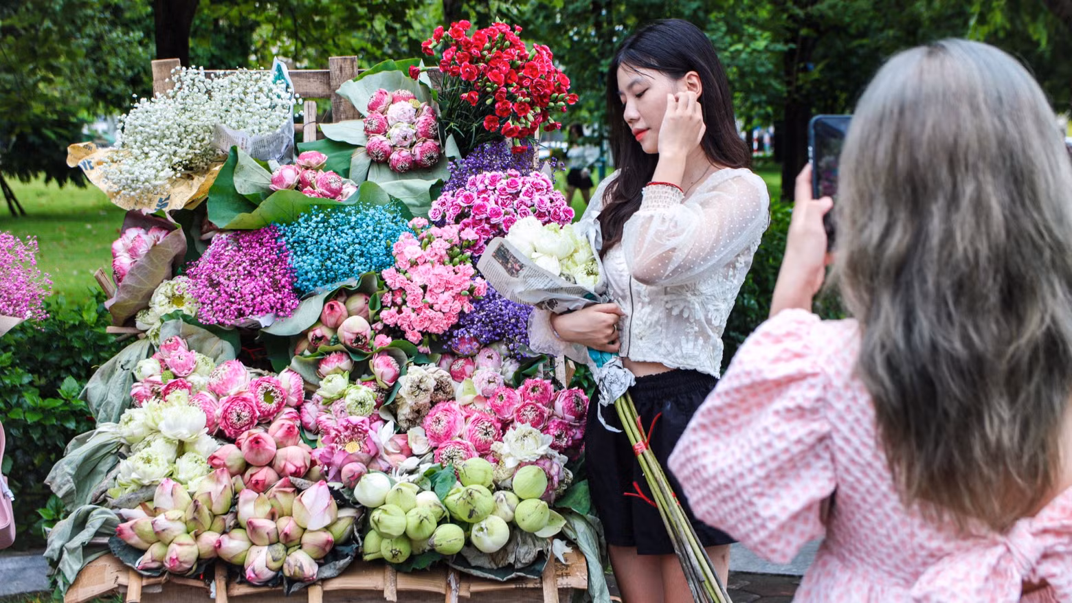 Des jeunes prennent des photos devant les vélos chargés de fleurs devant le parc de Lan Be. Photo: daidoanket Des jeunes prennent des photos devant les vélos chargés de fleurs devant le parc de Lan Be. Photo: daidoanket