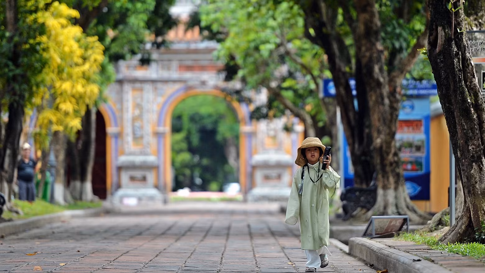 Une petite fille vêtue de l’ancien costume a suivi sa mère dans l'enceinte du Dai Nôi de Huê, en écoutant attentivement la présentation automatique via le dispositif du service touristique. Photo : nhandan.vn