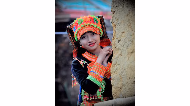 En costumes traditionnels sophistiqués à côté de la maison traditionnelle aux murs en torchis « nhà trình tường », il s’agit d’un portrait d’une fille de l’ethnie Dao rouge dans les hautes terres de Lai Châu. Photo : baodantoc.vn