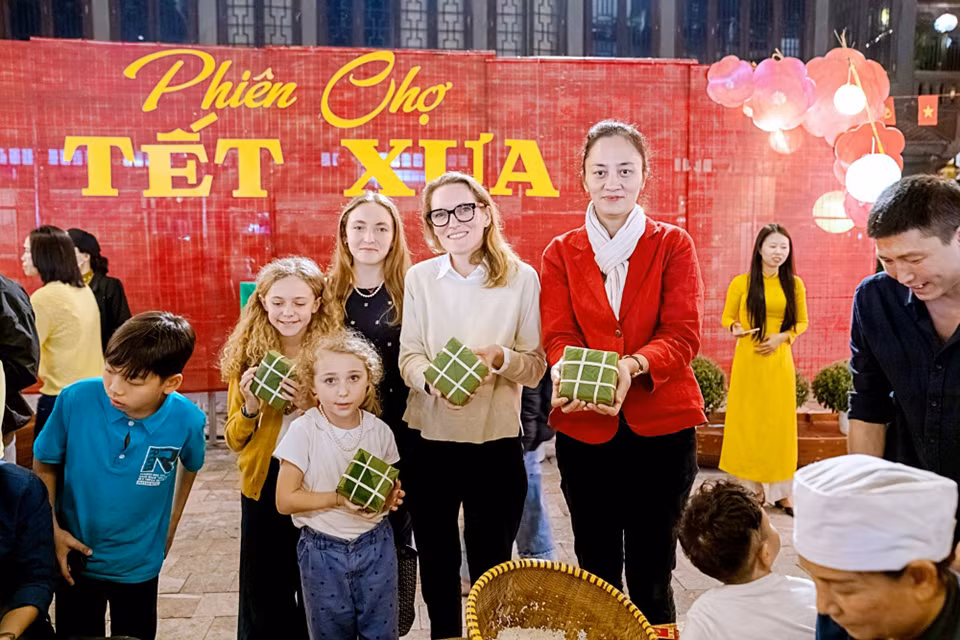Les visiteurs internationaux font l'expérience de l'emballage du "bánh chưng" lors e la reconstitution du Têt d’antan et le marché traditionnel de l’ancienne capitale de Hoa Lu. Photo : Service du Tourisme de Ninh Binh.