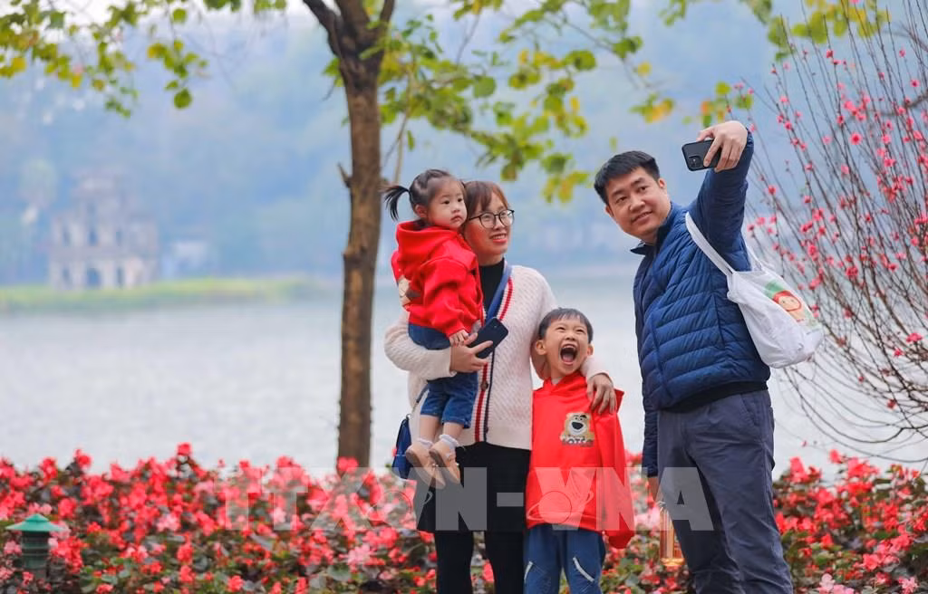 Une famille pose au bord du lac Ho Guom (Épée restituée) à Hanoi. Photo : VNA. Une famille pose au bord du lac Ho Guom (Épée restituée) à Hanoi. Photo : VNA.