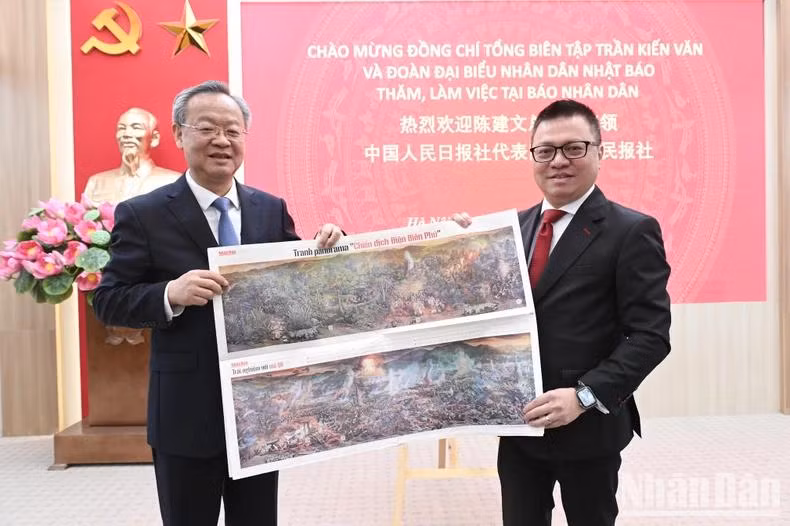 Le camarade Lê Quôc Minh présente au camarade Chen Jianwen le supplément illustré en panorama sur la Campagne de Diên Biên Phu.
