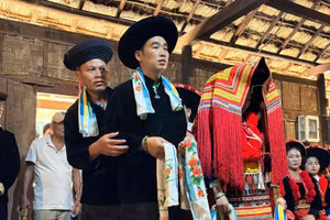 Les mariés dao rouge se tiennent devant l’autel des ancêtres, tandis que le maître de cérémonie et ses deux assistants accomplissent les rites pour le mariage. Photo : Vietnamnet.