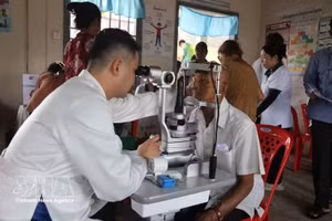 Un médecin examine le fond d’œil d’un habitant cambodgien. Photo : VNA.
