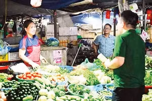 Au marché de Dong Xa (dans la capitale vietnamienne Hanoi), des employés de VPBank accompagnent des commerçants dans l’ouverture d’un compte dédié à leur activité directement sur leur étal. (Photo : MAI HA)