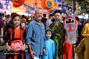 Des touristes internationaux s'imprègnent de l'ambiance de la Fête de la mi-automne au bord du lac Hoan Kiem, entourés de jouets traditionnels colorés. Photo : VNA.