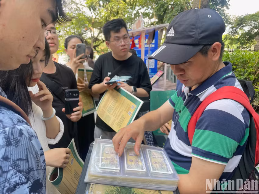 M. Vinh partage sa passion pour sa collection avec les jeunes visiteurs intéressés. Photo : Nhân Dân.
