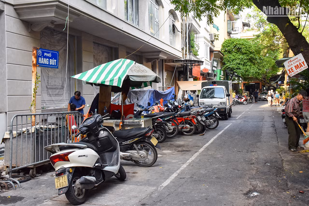 La rue Hàng But mesure 68 m de long et traverse les rues Thuôc Bac et Bat Su. Auparavant, elle appartenait au village de Dông Thanh, canton de Tiên Tuc, ancien district de Tho Xuong. Maintenant, elle fait partie du quartier de Hàng Bô (arrondissement de Hoàn Kiêm). Pendant la période coloniale française, cette rue s’appelait la rue Combanère, en 1945, son nom a été changé en Hàng But (Pinceaux). Dans le passé, la rue Hàng But s’appelait Hàng Mun, car elle se spécialisait dans la vente des morceaux de tissu pour les tailleurs afin de coudre des vêtements, des chapeaux, des chaussettes et des sacs-amulettes que les enfants portent lors de la fête de la mi-automne et du Têt Doan Ngo survenant le 5e jour du 5e mois lunaire. Elle développe aujourd’hui un commerce animé de biens de consommation et de services.