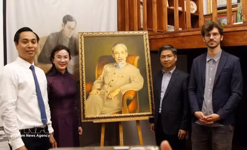 La directrice du site des vestiges du président Hô Chi Minh dans la zone du Palais présidentiel, Lê Thi Phuong, le directeur du Musée de l’Histoire vivante, Thomas Le Goff (premier rang, à droite) et d’autres membres de la délégation posent avec un grand portrait du Président Hô Chi Minh. Photo : VNA.
