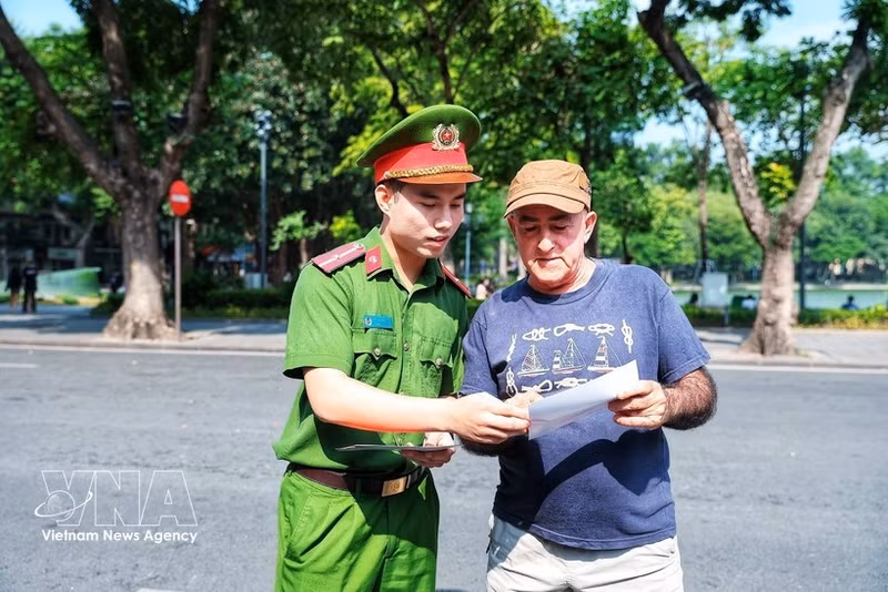 Des policiers présentent à un touriste étranger le kiosque « Station de police intelligente », facilitant ainsi l’accès des visiteurs étrangers aux services d’assistance des forces de police. Photo : VNA