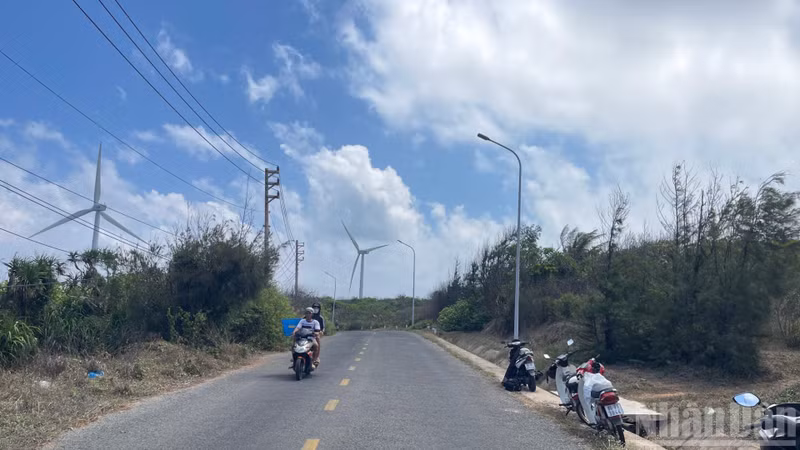 Une route prisée des touristes pour les photos, avec des éoliennes en arrière-plan.