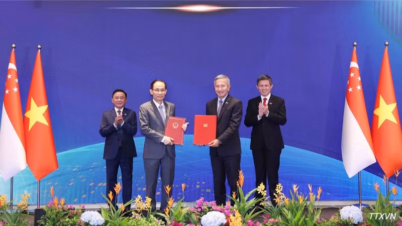 Le Hoai Trung, membre du Bureau politique et ministre des Affaires étrangères du Vietnam, et Vivian Balakrishnan, ministre singapourien des Affaires étrangères, échangent le protocole d’accord de coopération entre les deux partis. (Photo : Phương Hoa/VNA)