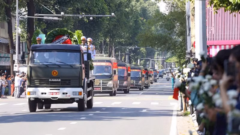 Le cortège transportant les restes des soldats traverse une haie d’habitants tenant des chrysanthèmes blancs. Photo : THE ANH.