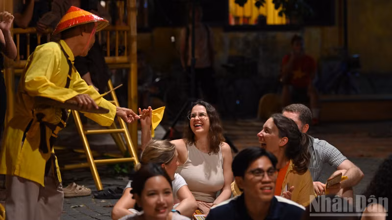 Des visiteurs étrangers découvrent avec enthousiasme les jeux traditionnels lors de leur séjour à Hoi An. Photo : NDEL.
