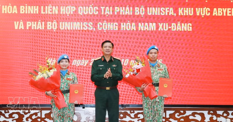 Le général de corps d’armée Nguyen Truong Thang, membre du Comité central du Parti et vice-ministre de la Défense (milieu), remet des décisions à deux officiers. Photo : VNA.