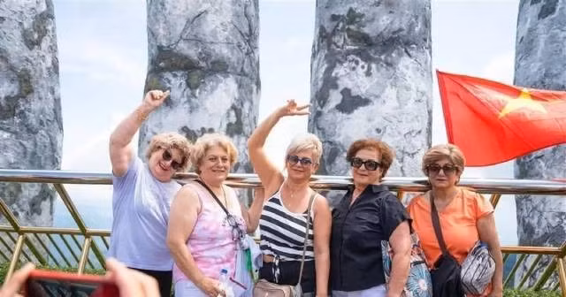 Les touristes étrangers apprécient de se prendre en photo sur le pont d’Or, orné de drapeaux vietnamiens éclatants, dans la zone touristique. Photo : baoquocte.vn