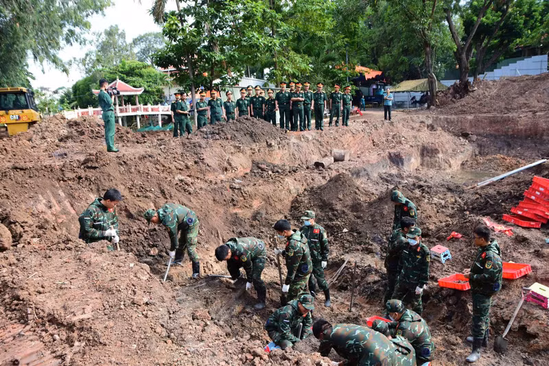 Les forces compétentes recherchent les restes de martyrs dans une fosse commune de plus de 30 m de long au parc Le Thi Rieng. Photo : Nguyen Hung.