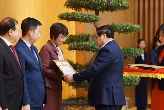 Le Premier ministre Pham Minh Chinh remet le certificat de mérite du Comité du Parti du gouvernement à Vu Viet Trang, directrice générale de l'Agence vietnamienne d'Information. Photo : VNA