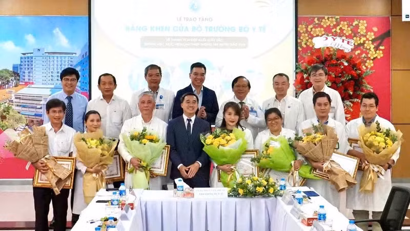 Le vice-ministre de la Santé, Tran Van Thuan, offre des fleurs et un certificat de mérite à l’équipe qui réalise une intervention fœtale sur une patiente singapourienne. Photo : nhandan.vn