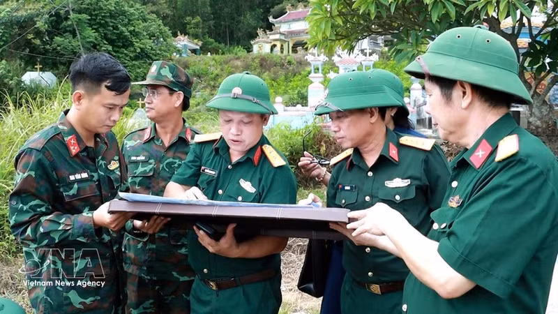 Le colonel Ha Van Ai, commissaire politique adjoint du Commandement militaire de la ville de Hue (3e à partir de la gauche), indique sur la carte l’emplacement présumé de la sépulture d’un martyr. Photo : VNA