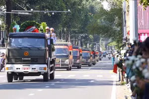 Le cortège transportant les restes des soldats traverse une haie d’habitants tenant des chrysanthèmes blancs. Photo : THE ANH.