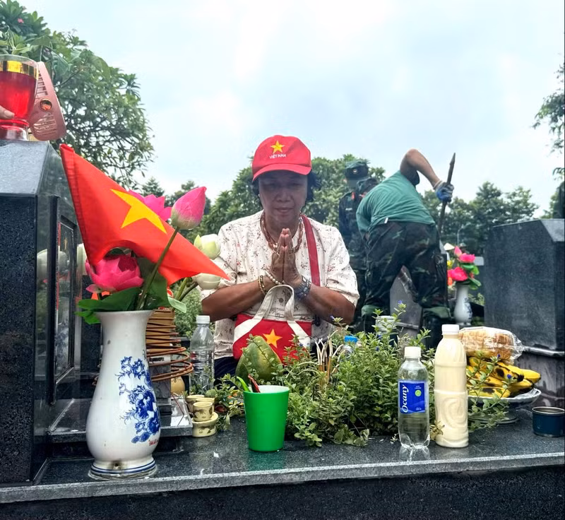 Mme Truong Thi Binh, 74 ans, à Hanoï, allume avec recueillement de l’encens sur la tombe de son oncle, le martyr Truong Nghe, au cimetière des martyrs de Mai Dich. Photo : Hanoimoi.