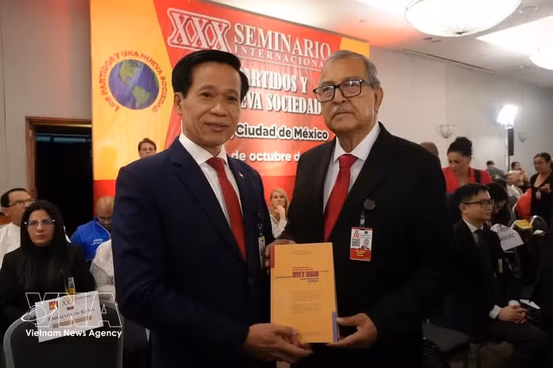 Hoang Phuc Lam, professeur associé et docteur, directeur adjoint de l’Académie nationale de politique Ho Chi Minh remet le livre à un membre du Parti du Travail du Mexique. Photo : VNA.