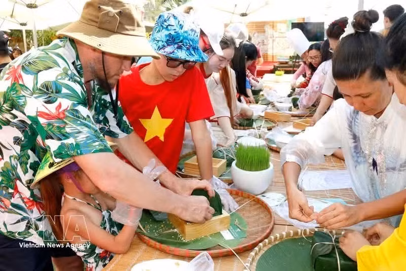 Des touristes étrangers participent à la préparation de banh chung. Photo : VNA.