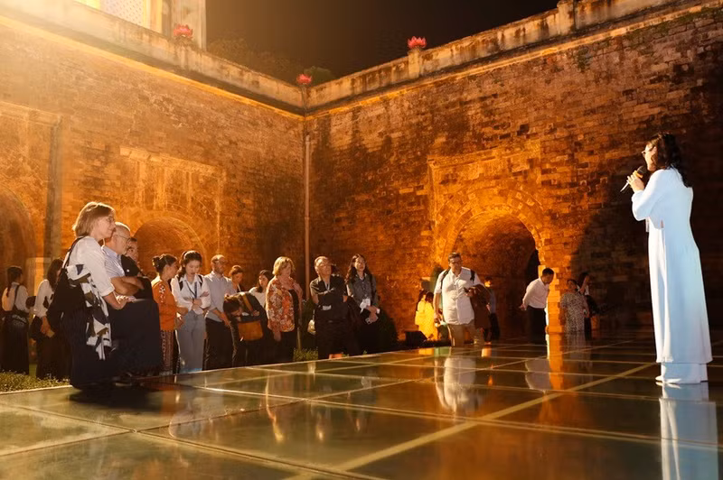 Des visiteurs étrangers vivent une expérience unique en découvrant la Citadelle impériale de Thang Long lors d’une visite nocturne. Photo : Hanoimoi.