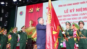 Le secrétaire général du Parti To Lam épingle l’insigne de Héros des Forces armées populaires sur le drapeau traditionnel du Département général de l’industrie de la défense. Photo : VNA.