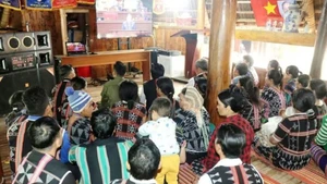 Des habitants de la commune frontalière d'A Vuong suivent la retransmission en direct de la séance d'ouverture du XIVe Congrès national du Parti à la maison Guol. Photo : VNA.