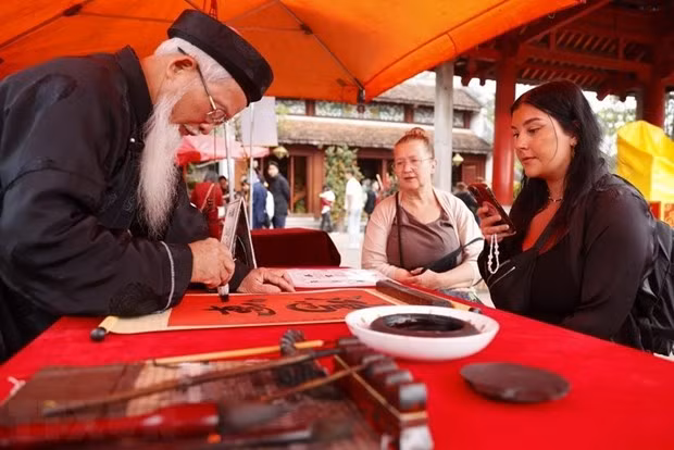 Des visiteurs étrangers demandent des calligraphies. Photo : VNA Des visiteurs étrangers demandent des calligraphies. Photo : VNA