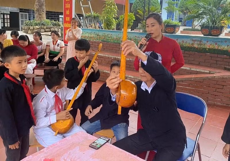 L’artisan Thùng Van Dôi présente les différentes parties du đàn tính, l’instrument traditionnel du peuple Thaï, aux élèves de l’école semi-internat de Chà Nua.