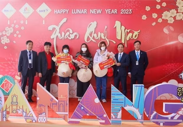 Des représentants du Service du Tourisme de Dà Nang et de l’aéroport de Dà Nang offrent des fleurs et cadeaux à des passagers du vol VZ964. Photo : VNA.