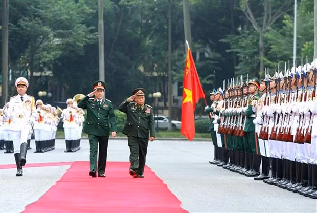 Le chef du Département général de la politique de l’Armée populaire du Vietnam, Luong Cuong, et son homologue lao Thongloi Silivong passent en revue une garde d’honneur. Photo : VNA