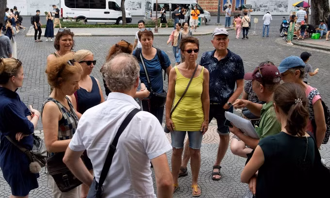 Touristes étrangers écoutant un guide devant la Poste centrale de Saïgon, le 18 juin 2023. Photo: VnExpress 