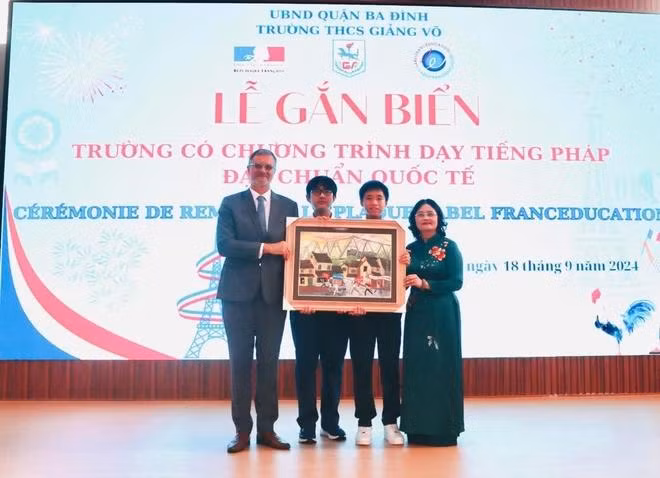 La directrice du collège Giang Vo, Tô Thi Hai Yên, et ses élèves remettent un cadeau à l'ambassadeur de France au Vietnam, Olivier Brochet. Photo : CTV/CVN.