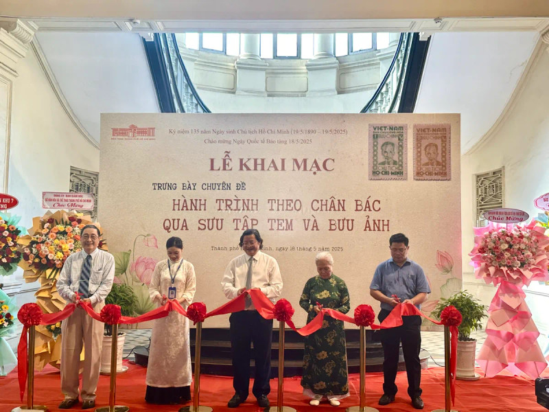 Des délégués coupent le ruban inaugural de l'exposition thématique "Sur les traces de l'Oncle Hô à travers une collection de timbres et de cartes postales". 