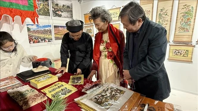 L’artisan Nguyên Dang Tâm présente au public les matériaux et les moules en bois, tout en expliquant la technique d’impression des estampes de Dông Hô. Photo : VNA