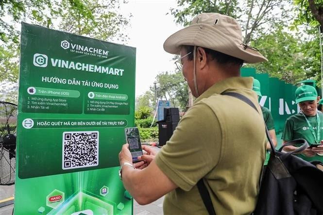Les gens scannent directement le code QR de la plateforme de commerce électronique VinachemMart dans la rue piétonne du lac Hoàn Kiêm. Photo : VNA.