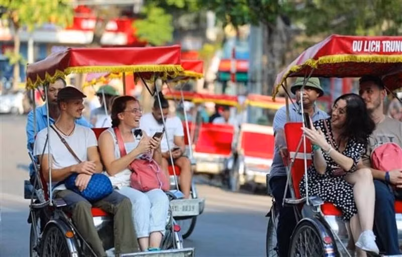 Des touristes étrangers prennent un cyclo-pousse pour découvrir le Vieux quartier de Hanoi. Photo : VNA.