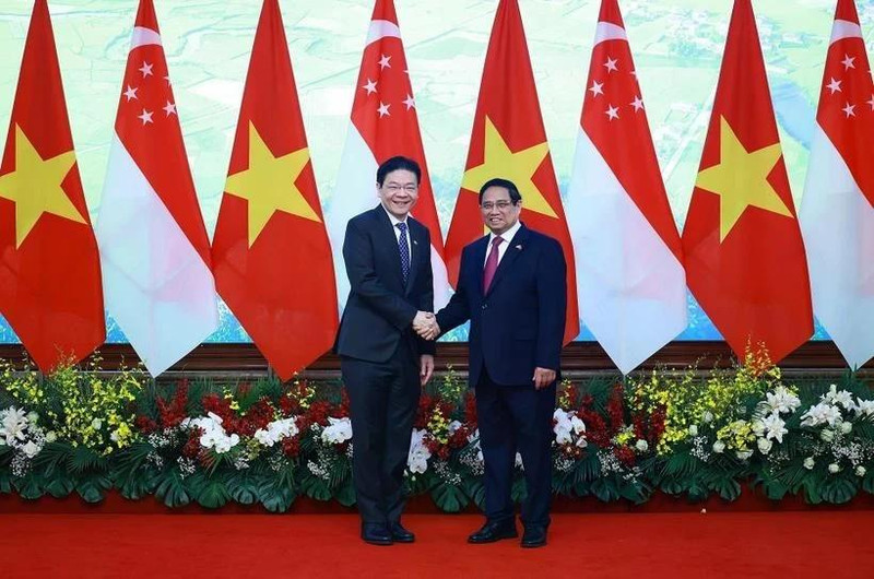 Le Premier ministre Pham Minh Chinh (à droite) et son homologue singapourien Lawrence Wong se serrent la main, à Hanoï, le 26 mars. Photo : VNA
