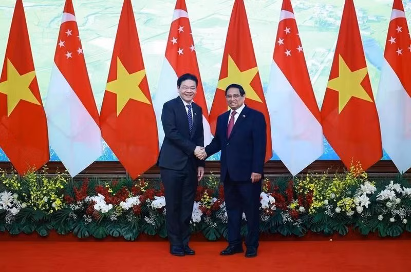 Le Premier ministre Pham Minh Chinh (à droite) et son homologue singapourien Lawrence Wong se serrent la main, à Hanoï, le 26 mars. Photo : VNA