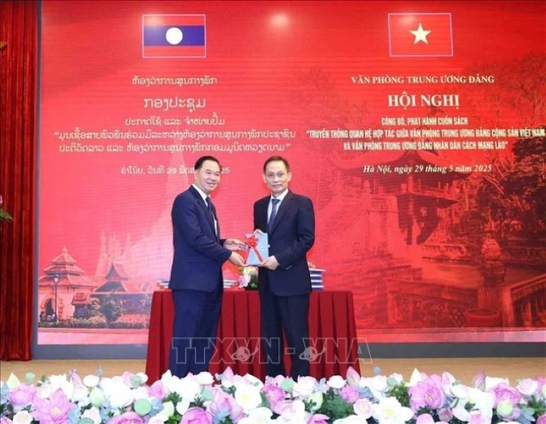 Le Hoai Trung (droite), secrétaire du Comité central du PCV et chef du Bureau du Comité central du PCV, offre un exemplaire du livre à Thongsalith Mangnomek, secrétaire du Comité central du PPRL et chef du Bureau du Comité central du PPRL. Photo : VNA.