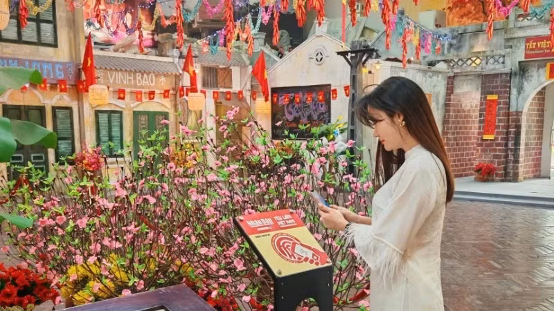 Une touriste découvre le panneau à puce NFC à la citadelle impériale de Thang Long. 