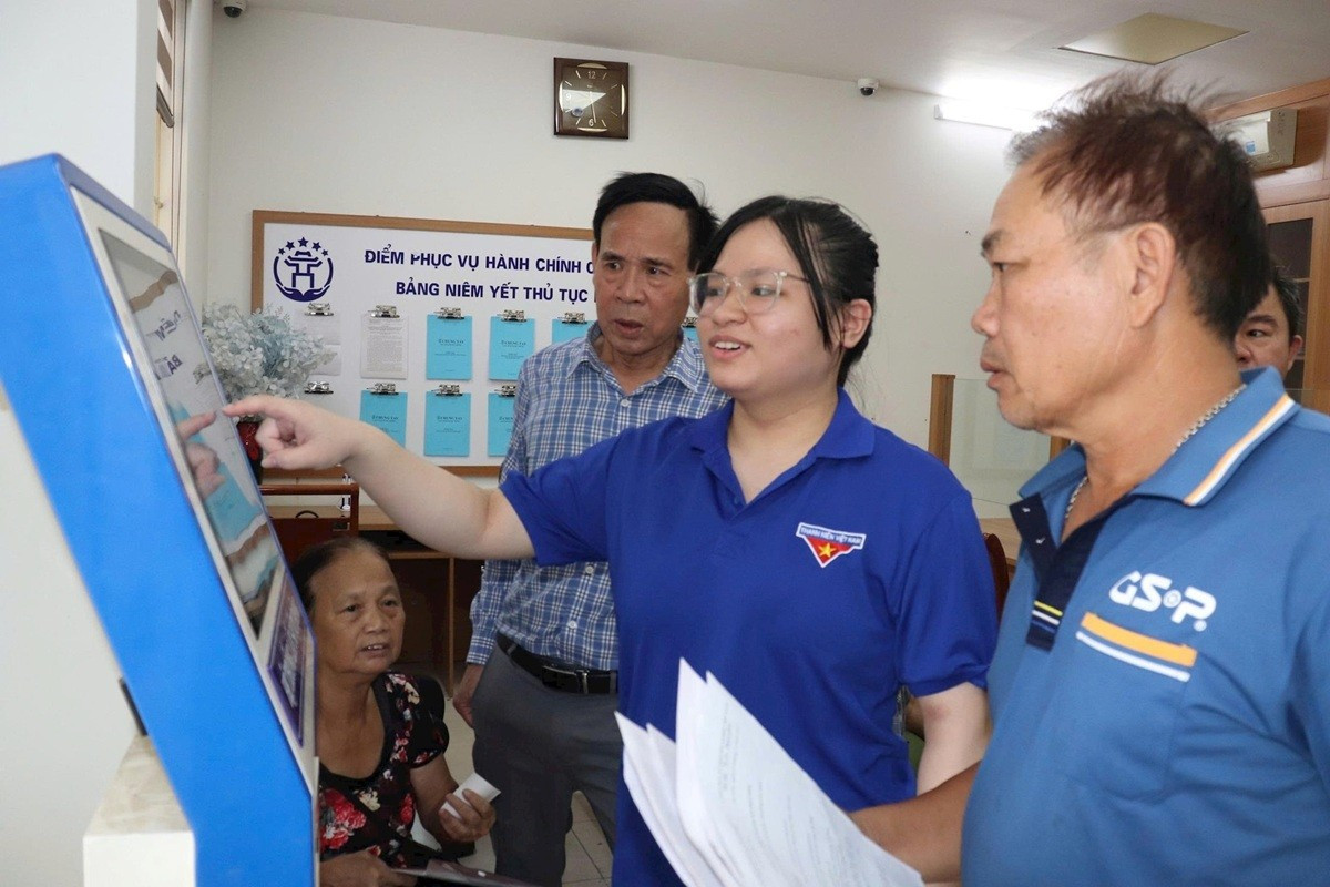 Les membres de l'Union des jeunes de la commune de Bat Trang aident les habitants au guichet de services administratifs publics de la commune. Photo : Phuong Loc. 