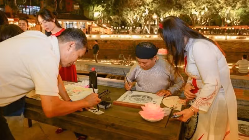 Des visiteurs s’initient à la calligraphie et demandent des caractères calligraphiés. (Photo : Bao Long)